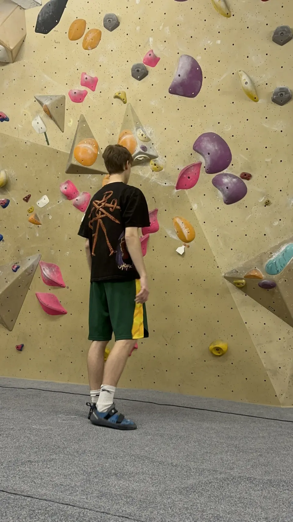 Climber studying a boulder problem on the wooden wall