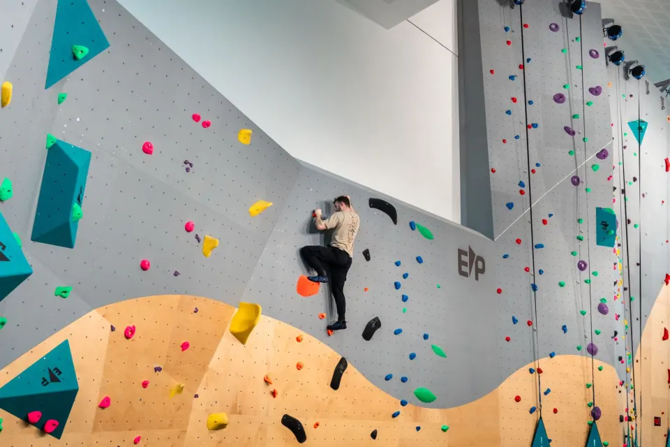Climber on the grey and orange bouldering wall at Jubilee