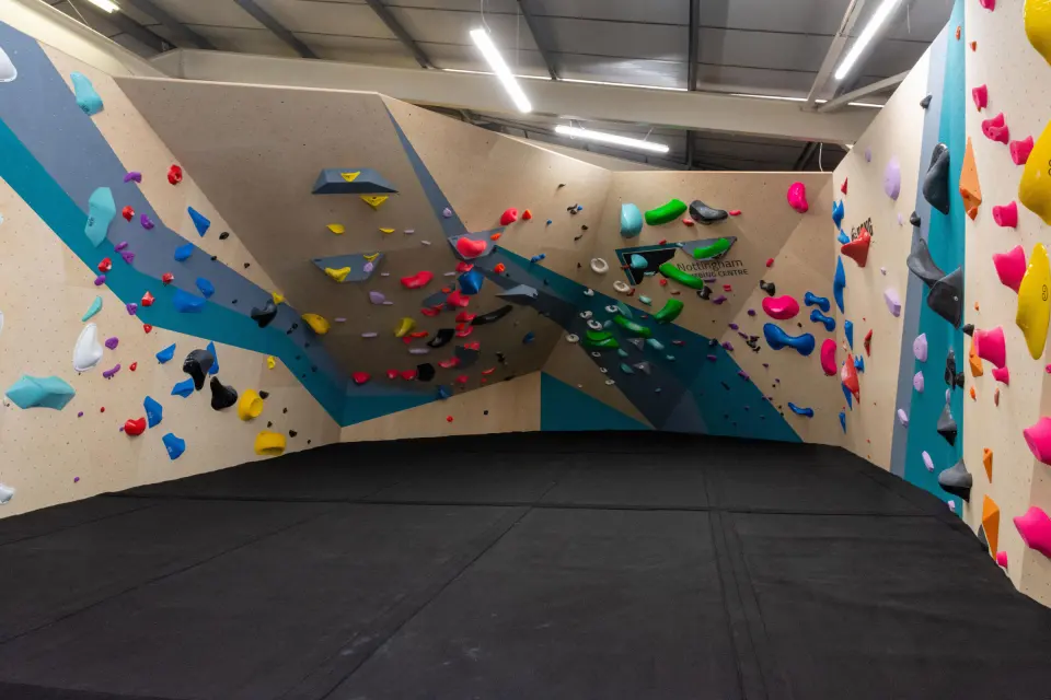 Bouldering walls with blue and grey volumes above black matting