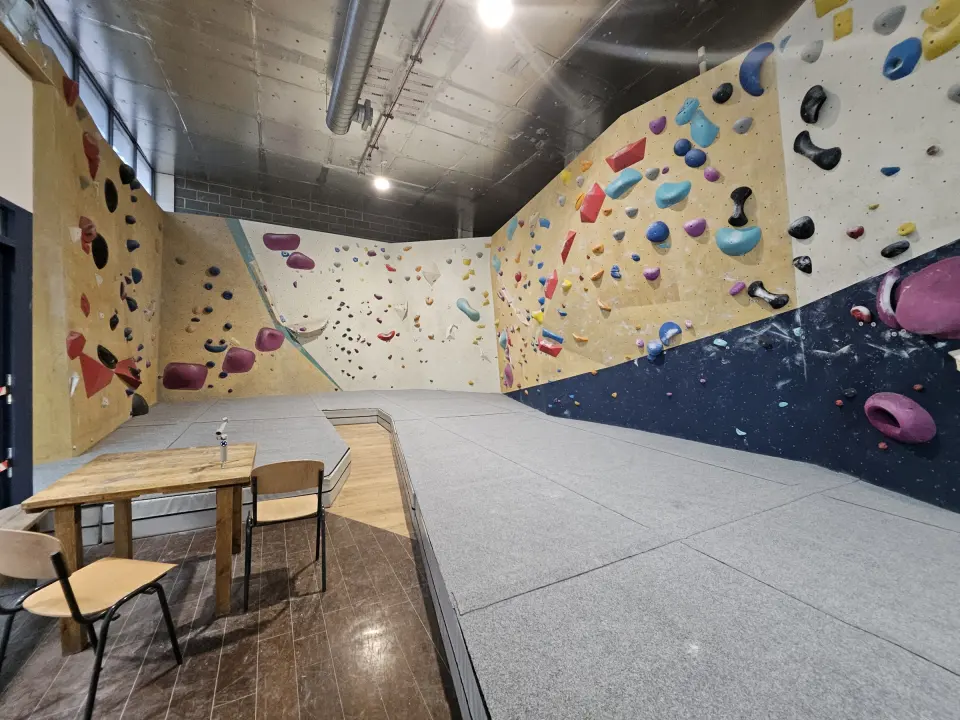 Corner of the bouldering floor with a table beside the mats