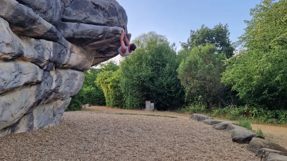 Climber on the steep overhanging side of a boulder
