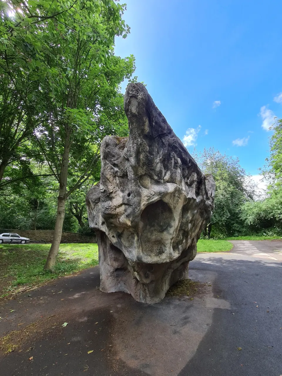 The steep prow of the boulder beside a park path