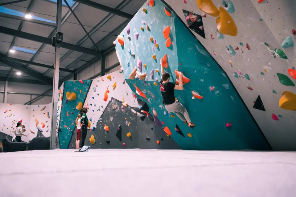 Climber on a steep teal bouldering wall at Flashpoint Cardiff