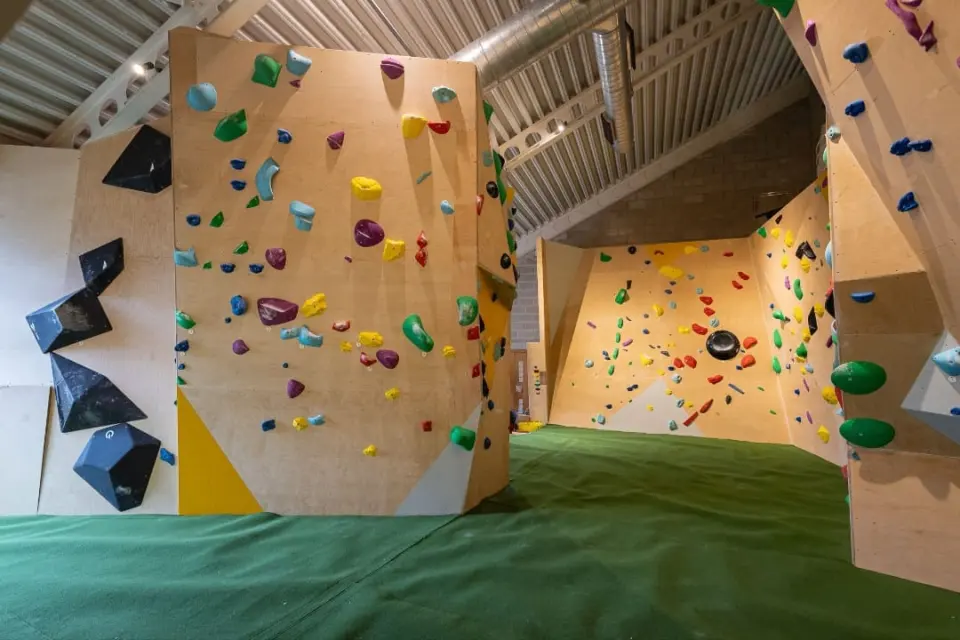 Plywood bouldering walls and a freestanding block over green matting