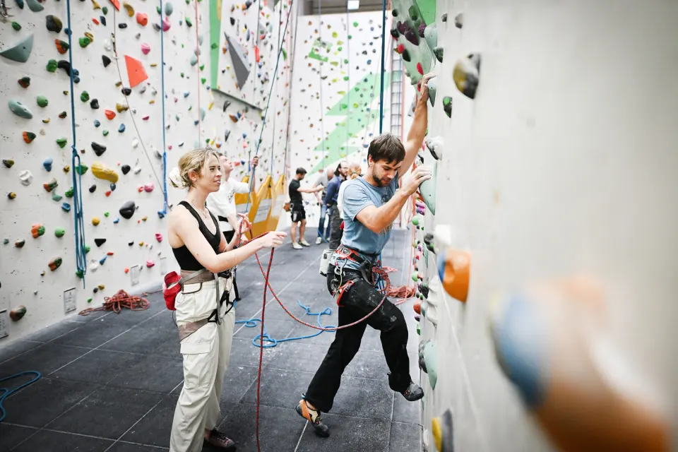 Climbers on top ropes beside the old stone pillars inside The Church climbing centre in St Werburgh's, Bristol