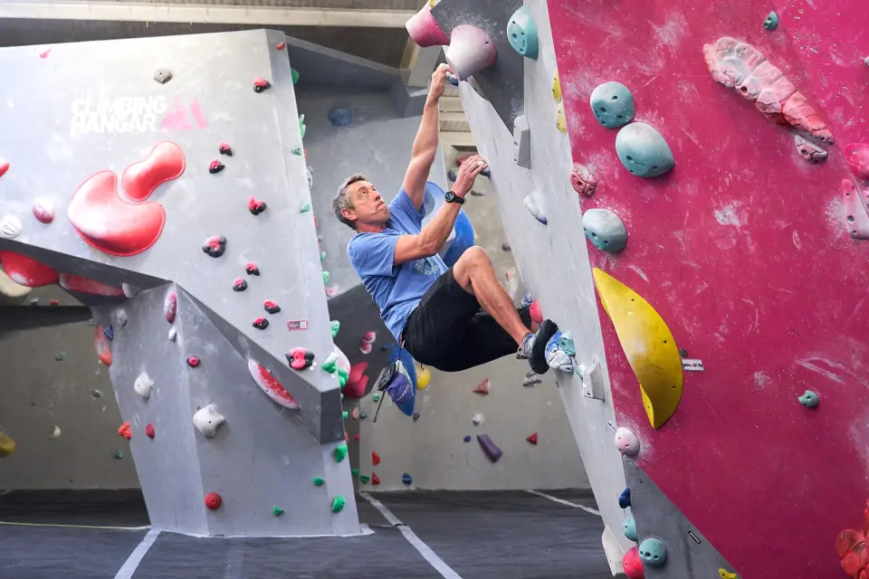 A climber on an overhanging pink and grey bouldering wall at The Climbing Hangar Plymouth