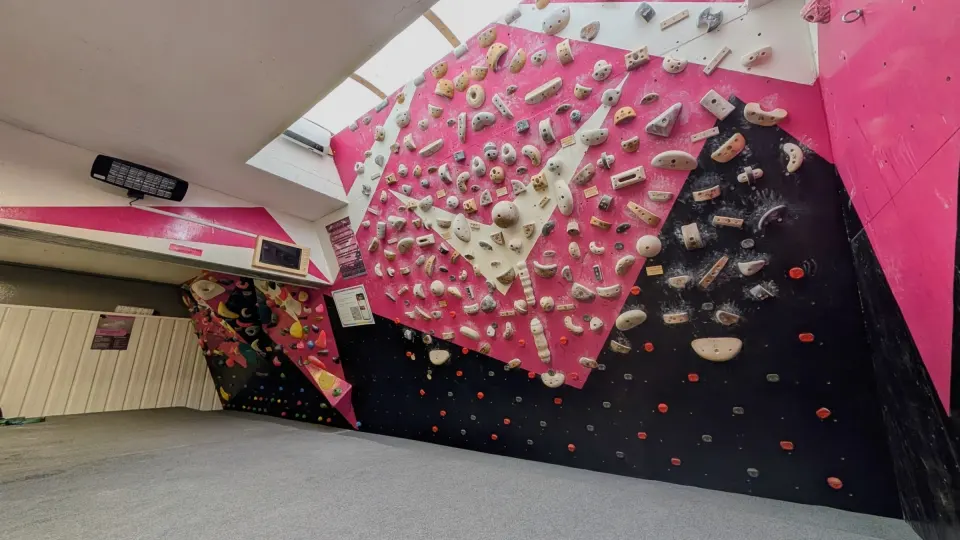 Pink and black bouldering walls with a training board at The Hangout on the Isle of Portland