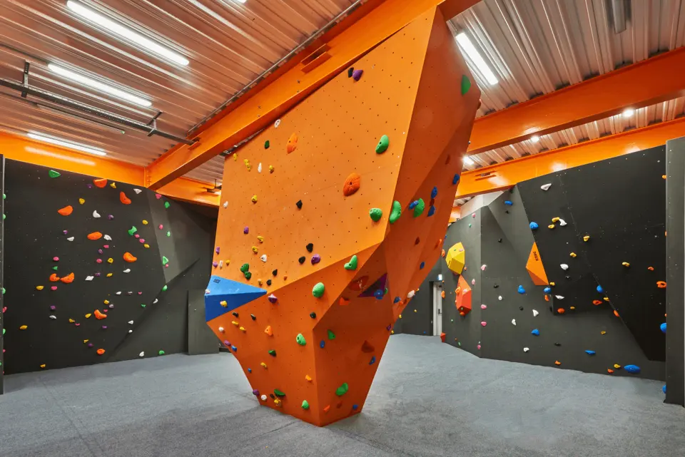 Orange boulder and dark bouldering walls under the roof beams in the bouldering area at F51 in Folkestone