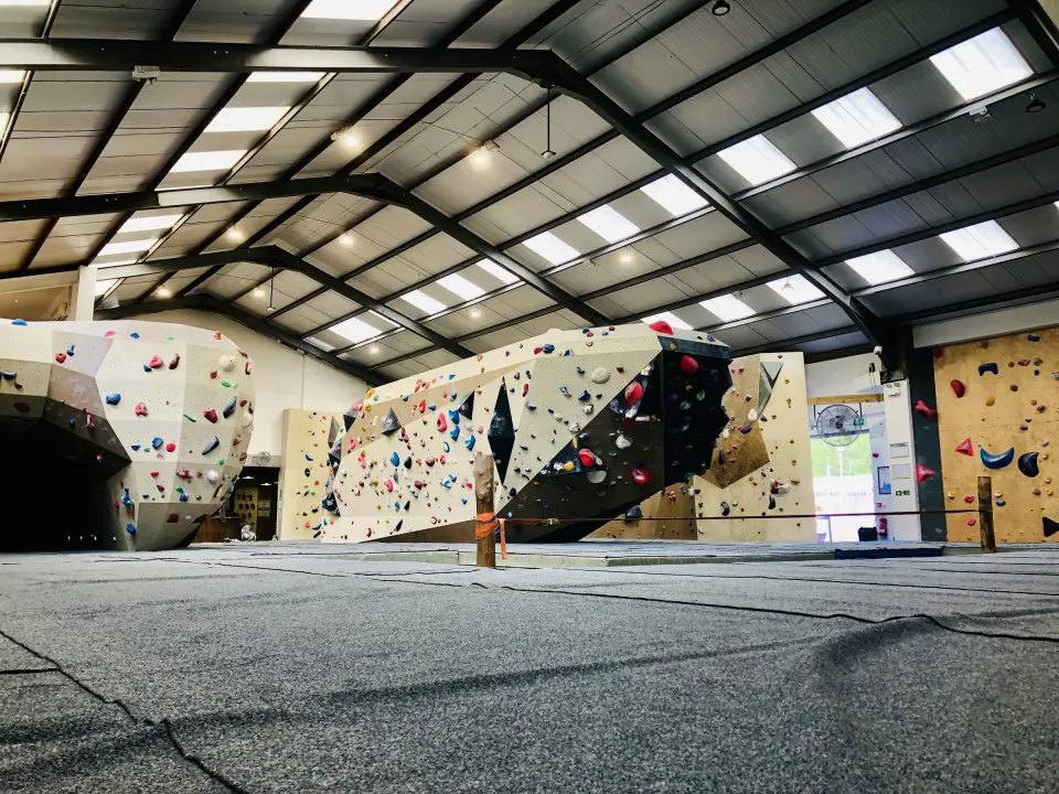 Long run of bouldering walls under a high warehouse roof