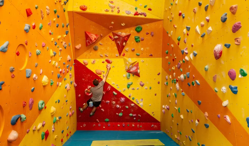 A boulderer reaching up a red and yellow wall at the RockFace bouldering wall in Dunfermline