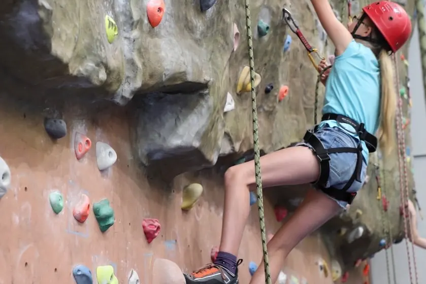 Top-rope climber below the wall's large rock-textured overhang