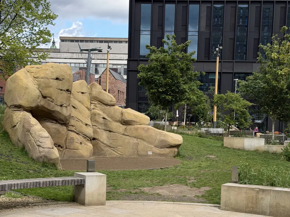 Sandstone-coloured sculpted boulder on a grassy bank in Pound's Park