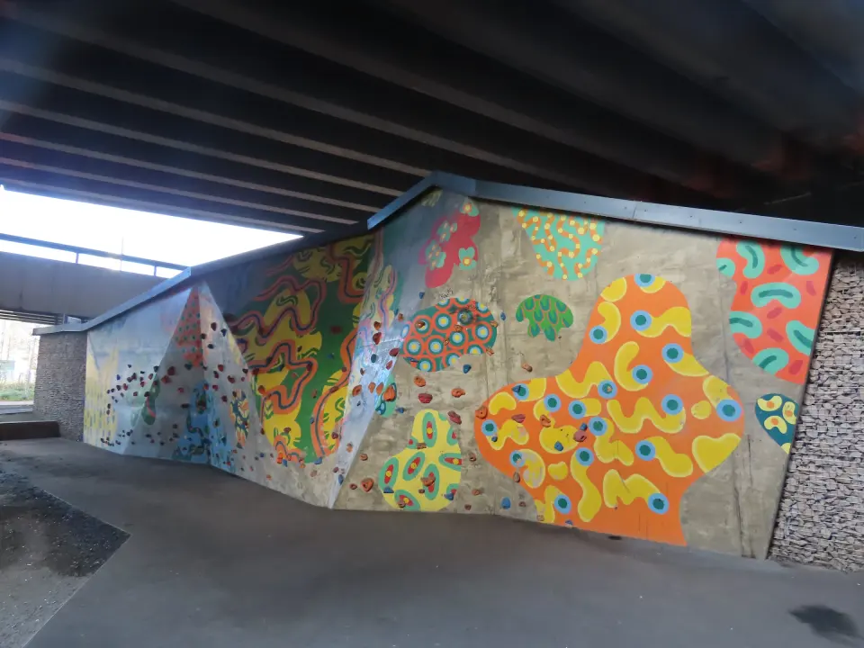 Painted concrete climbing wall with bolted holds under the ring road