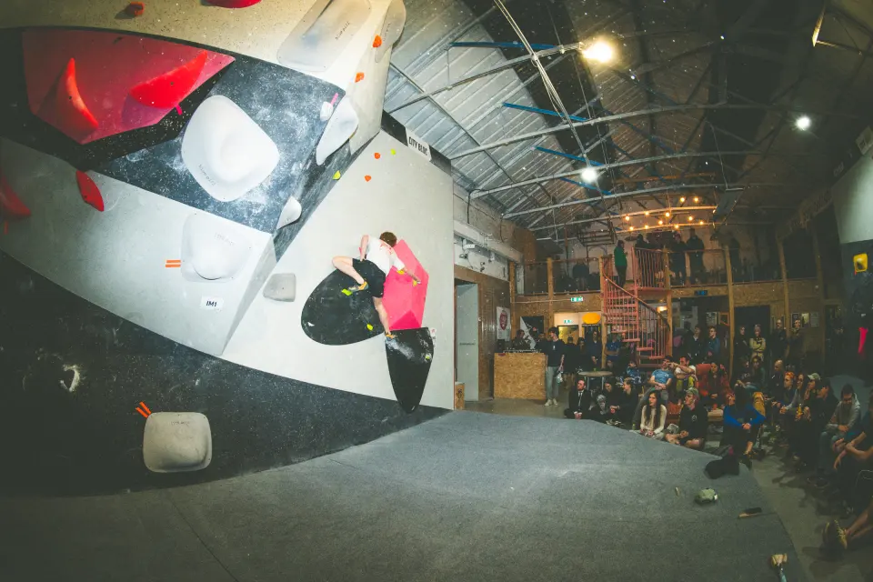 A boulderer on the competition wall at City Bloc in Leeds, watched by a crowd