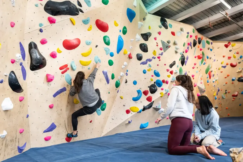 Climber on the main bouldering wall above blue matting