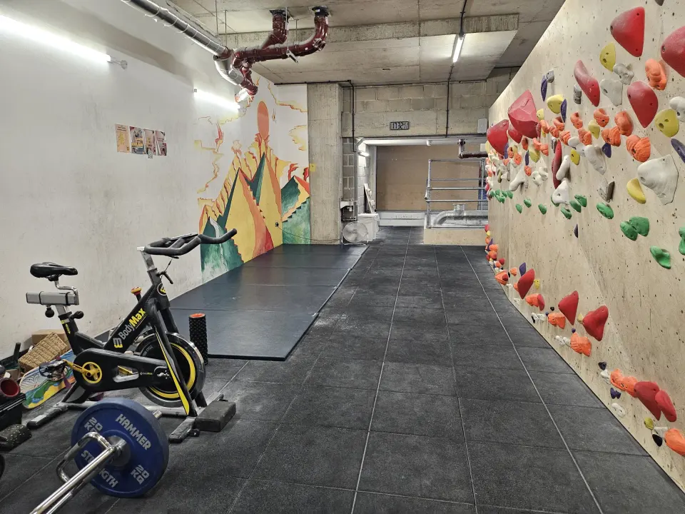 Traverse wall beside the gym area with bikes and weights