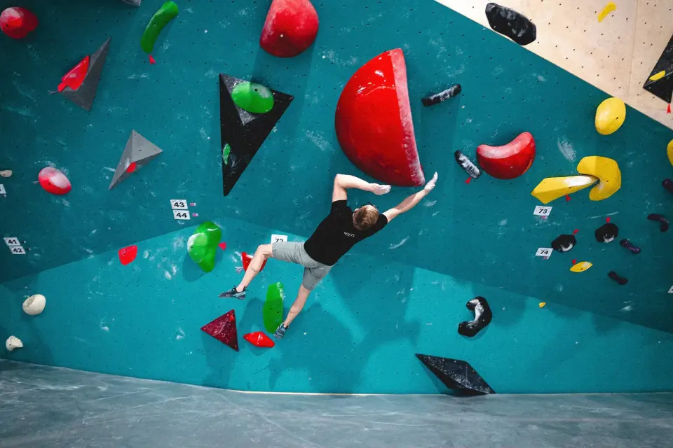Climber on the teal bouldering wall at the Hive Zagreb