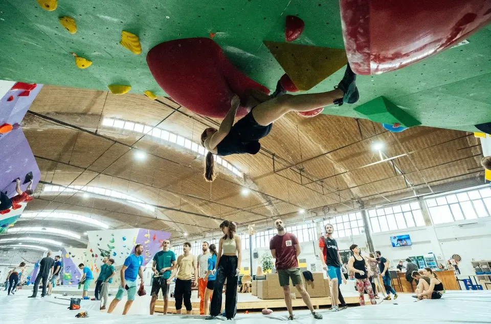 Climber beneath a roof with the wider Hive bouldering hall behind