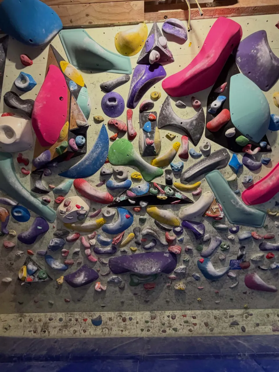 Densely set spray wall with colourful holds and blue matting at SPK Paklenica