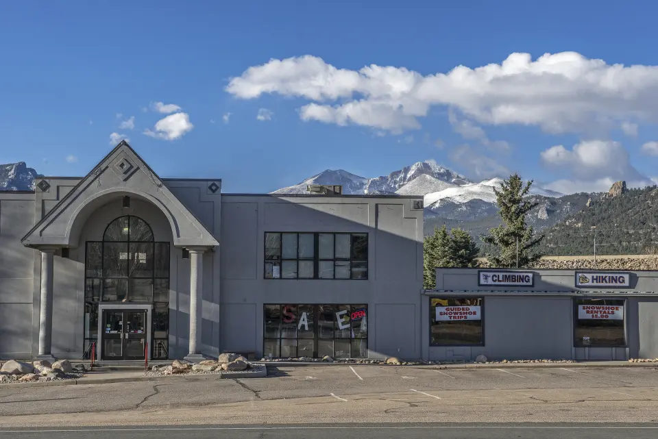 The Estes Park Mountain Shop building and its Climbing sign, with snowy peaks behind