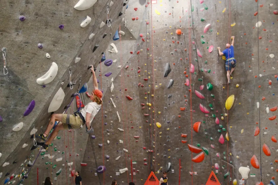 Climbers on the tall roped walls above the orange auto-belay gates