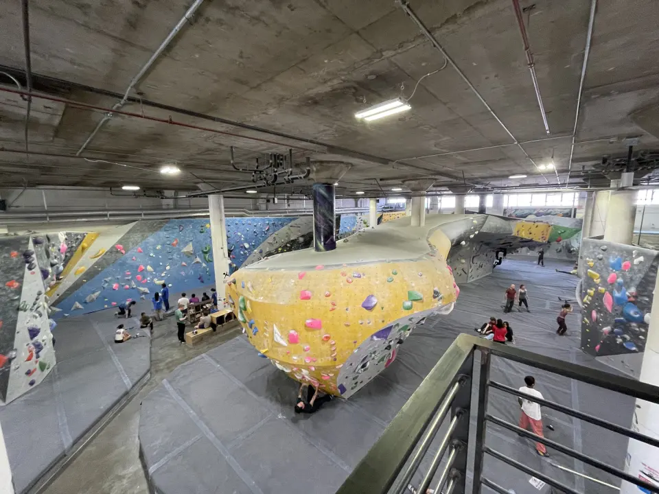 Bouldering hall seen from the mezzanine, with a large yellow boulder and long walls