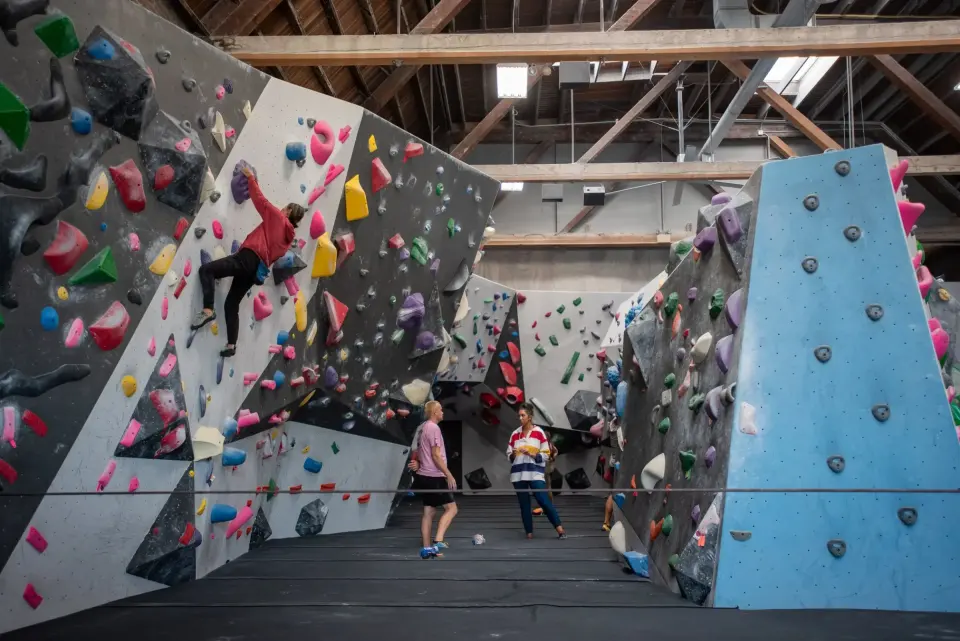 Climber on the angled bouldering walls under the wooden roof trusses