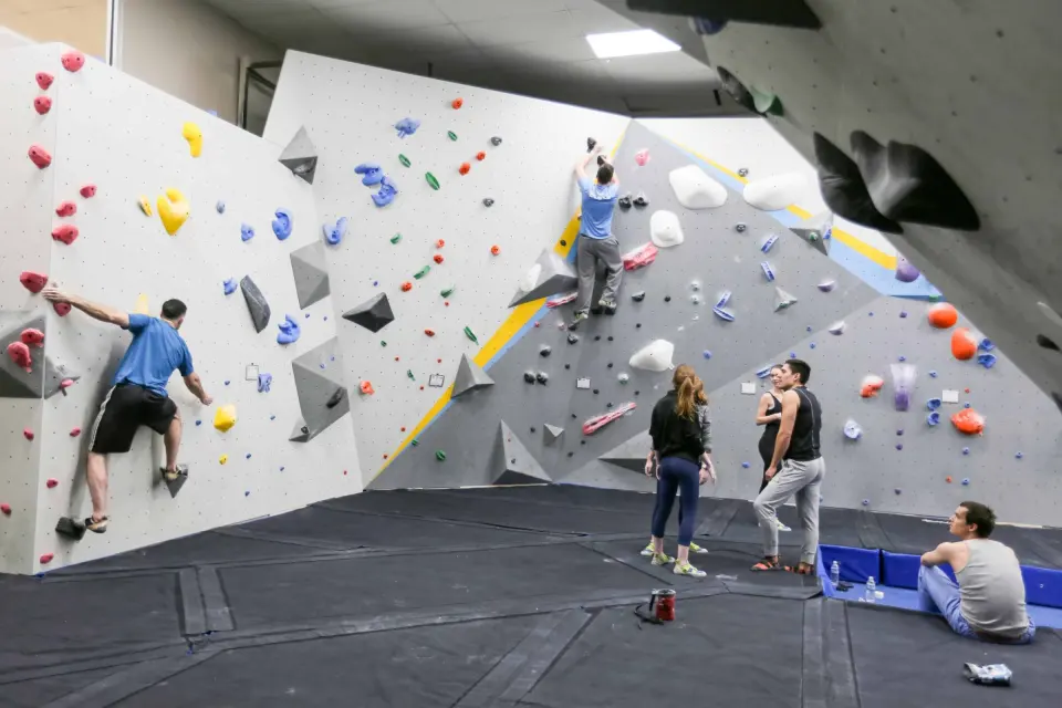 Bouldering walls with angled volumes and climbers on the mats