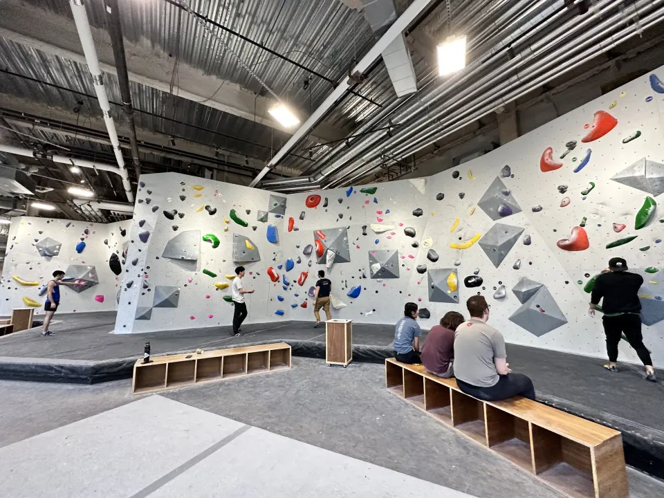 Climbers resting on benches by the long bouldering wall