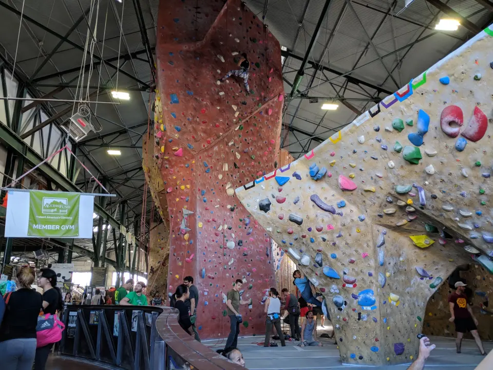 Tall roped walls and a red climbing tower under the steel roof