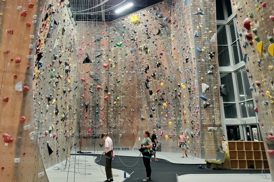 Tall sandstone-coloured lead walls in the main rope hall, with climbers and belayers below