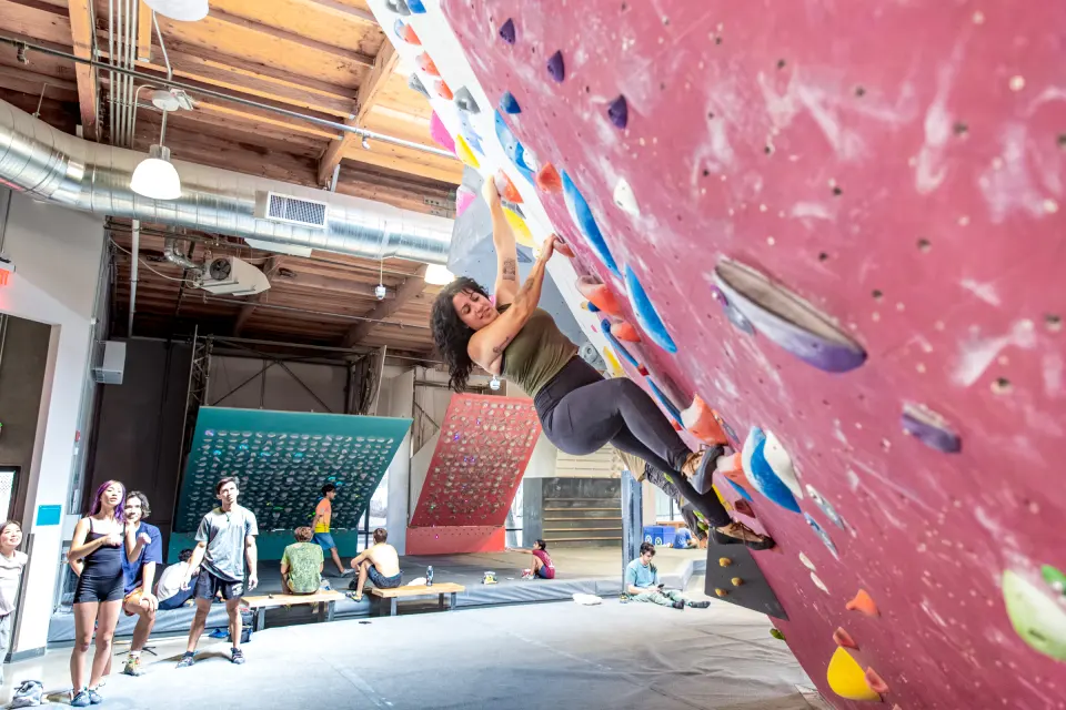 Climber on a steep pink wall with the training boards behind