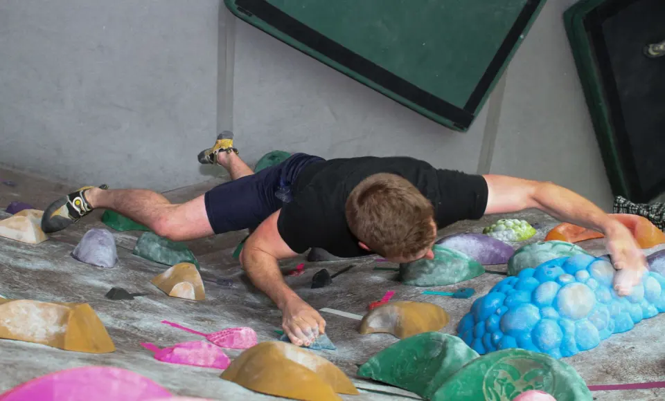Climber stretching between large holds on a low-angle boulder