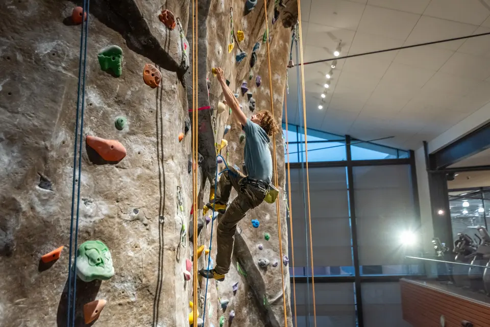 Climber on the tall textured top-rope wall beside the WREC's windows