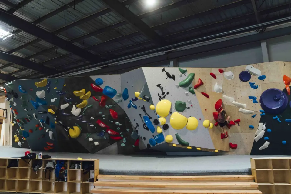 Long bouldering wall in grey, white and plywood panels in the new Seattle bouldering building