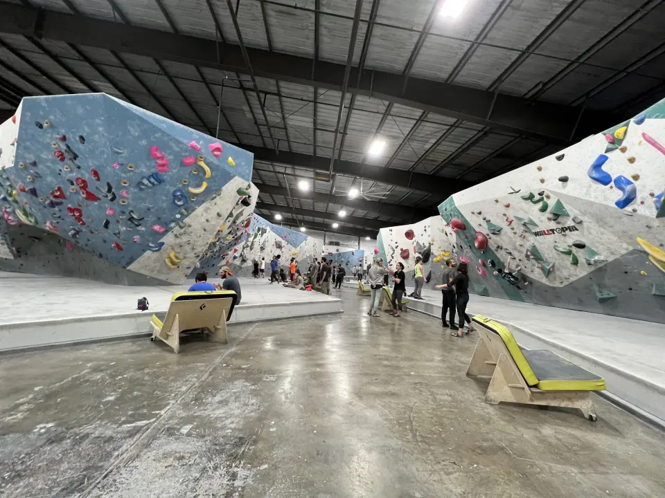 Rows of blue, white and teal bouldering walls along the gym floor