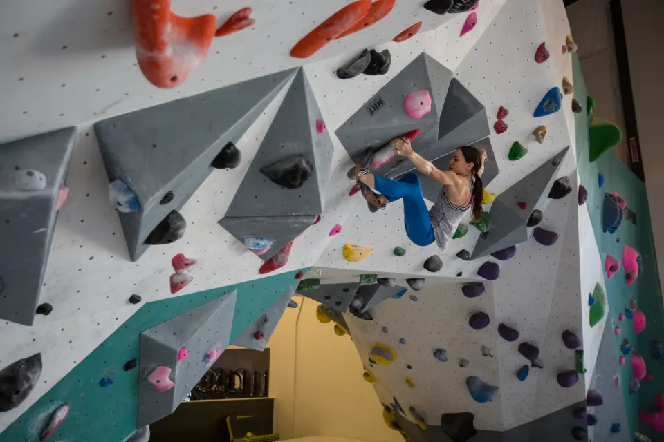 Climber moving between grey volumes on a white overhang