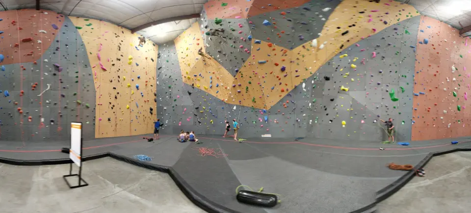 Main roped hall with orange, tan and grey walls and climbers on top ropes
