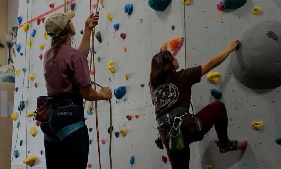 Belayer and climber on a top-rope route beside a large volume