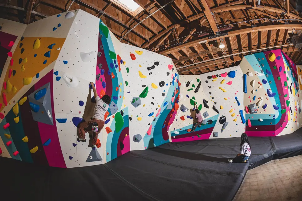 Climber on a multicoloured boulder above thick matting