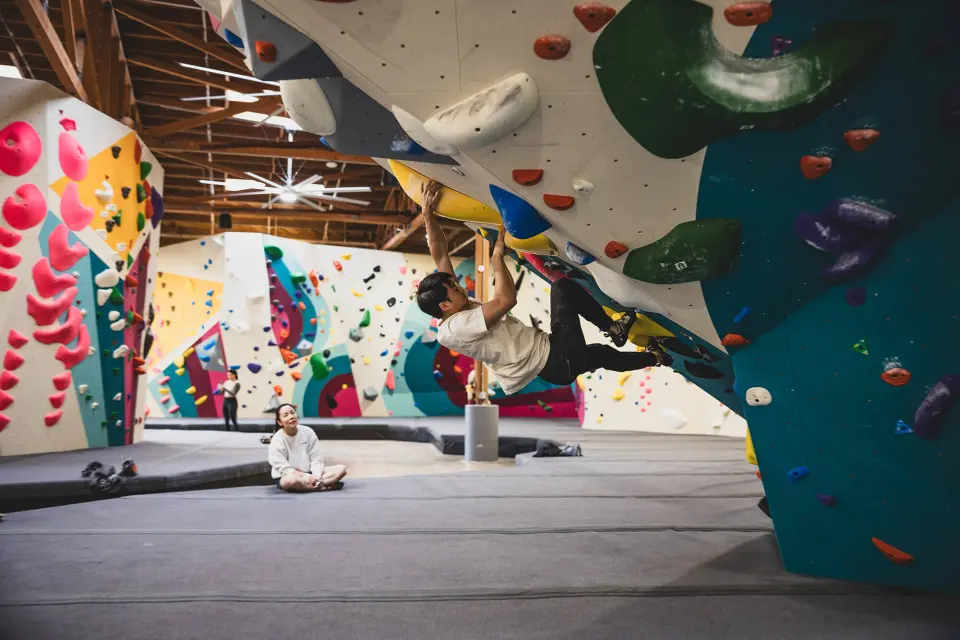 Climber on a steep overhang with big green and blue holds