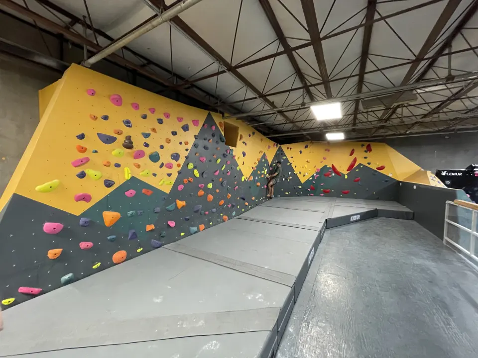 Long bouldering wall painted with yellow mountain peaks