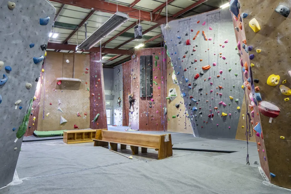 Climbing hall with roped walls, a training board and benches on the matting