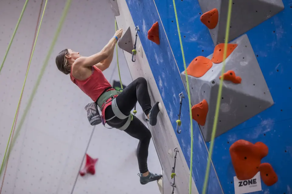 Lead climber on the blue wall with grey volumes