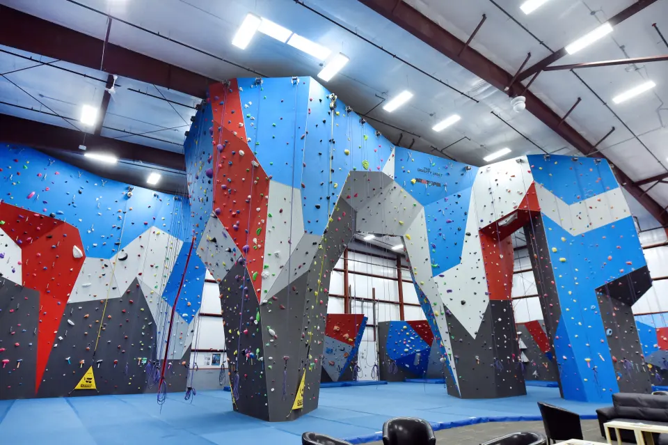 Tall red, blue and grey top-rope towers under the arched roof of the main hall