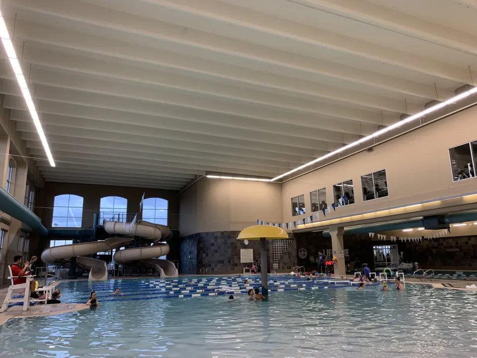 Indoor leisure pool with spiral water slides beneath tall arched windows