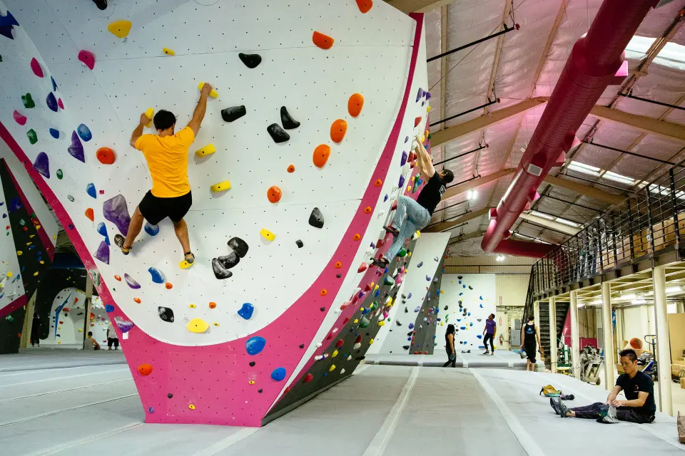Climbers on a white boulder with a pink base below the mezzanine