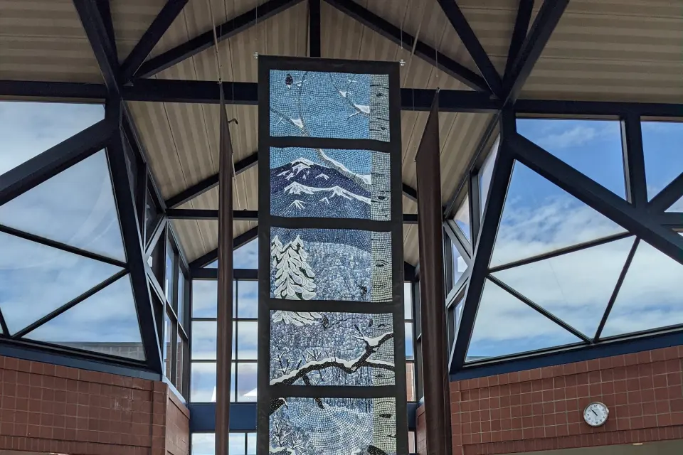 Glazed atrium of the recreation centre with a hanging mosaic of mountains and trees