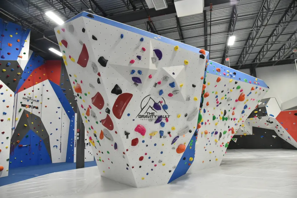 White bouldering block with the Gravity Vault logo, roped walls behind