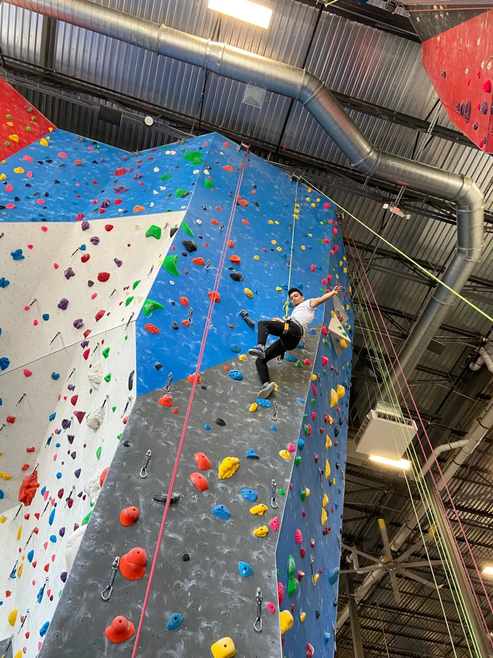 Climber on a steep red and grey roped wall